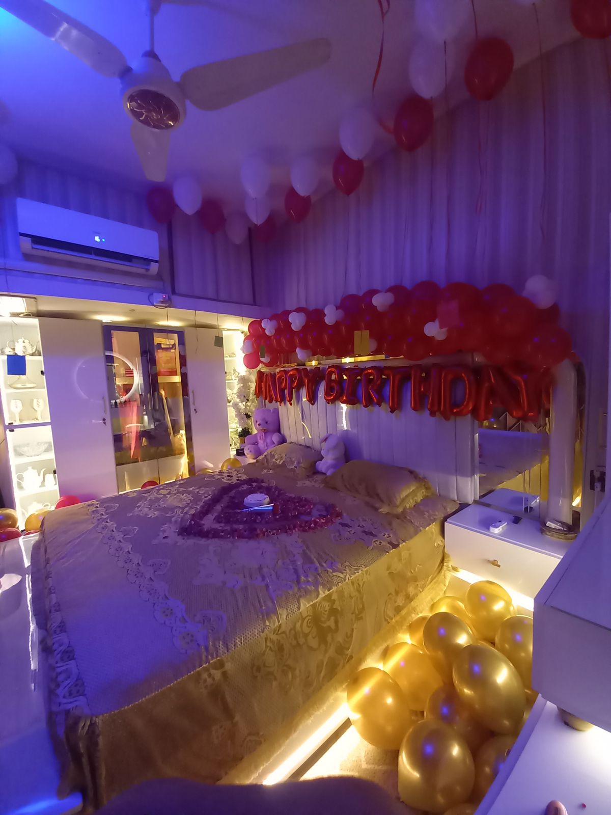Romantic birthday bedroom decoration Karachi with red white balloons and rose petal heart on bed – image 1
