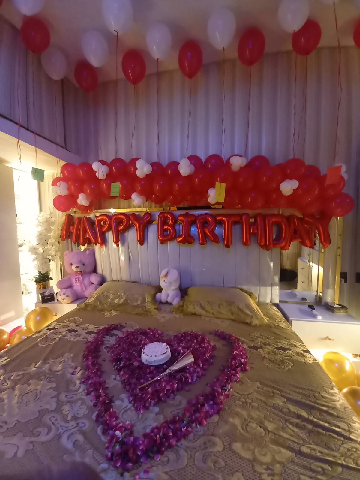 Romantic birthday bedroom decoration Karachi with red white balloons and rose petal heart on bed – image 3