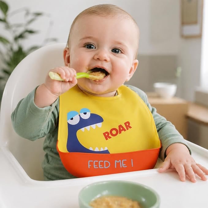 Baby in high chair with yellow dino feeding bib